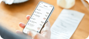 Pessoa segurando um celular que mostra uma lista de solicitações de reembolso, com interface clara e intuitiva, destacando a gratuidade da solução.